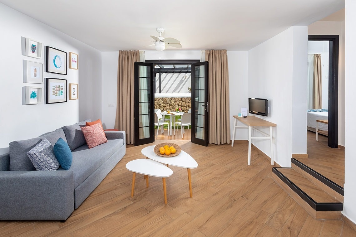 a living room with a gray couch and two white tables