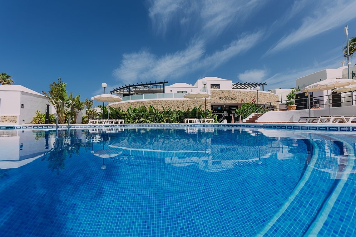 a woman in a bathing suit sits on the edge of a swimming pool