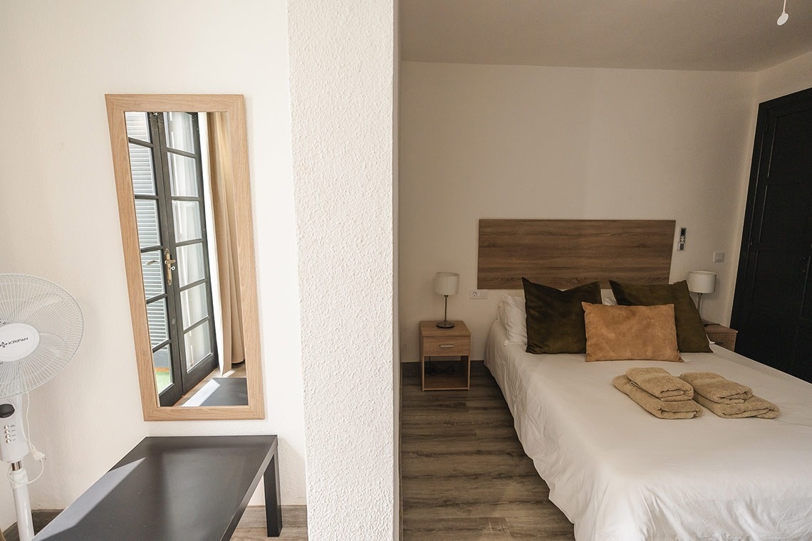 a bedroom with a fan and a mirror and a bed