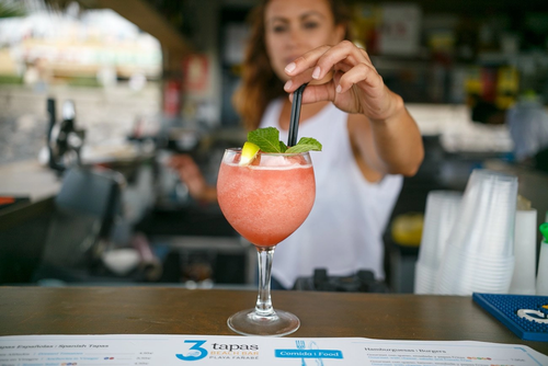 a person holding a martini in front of an infinity pool