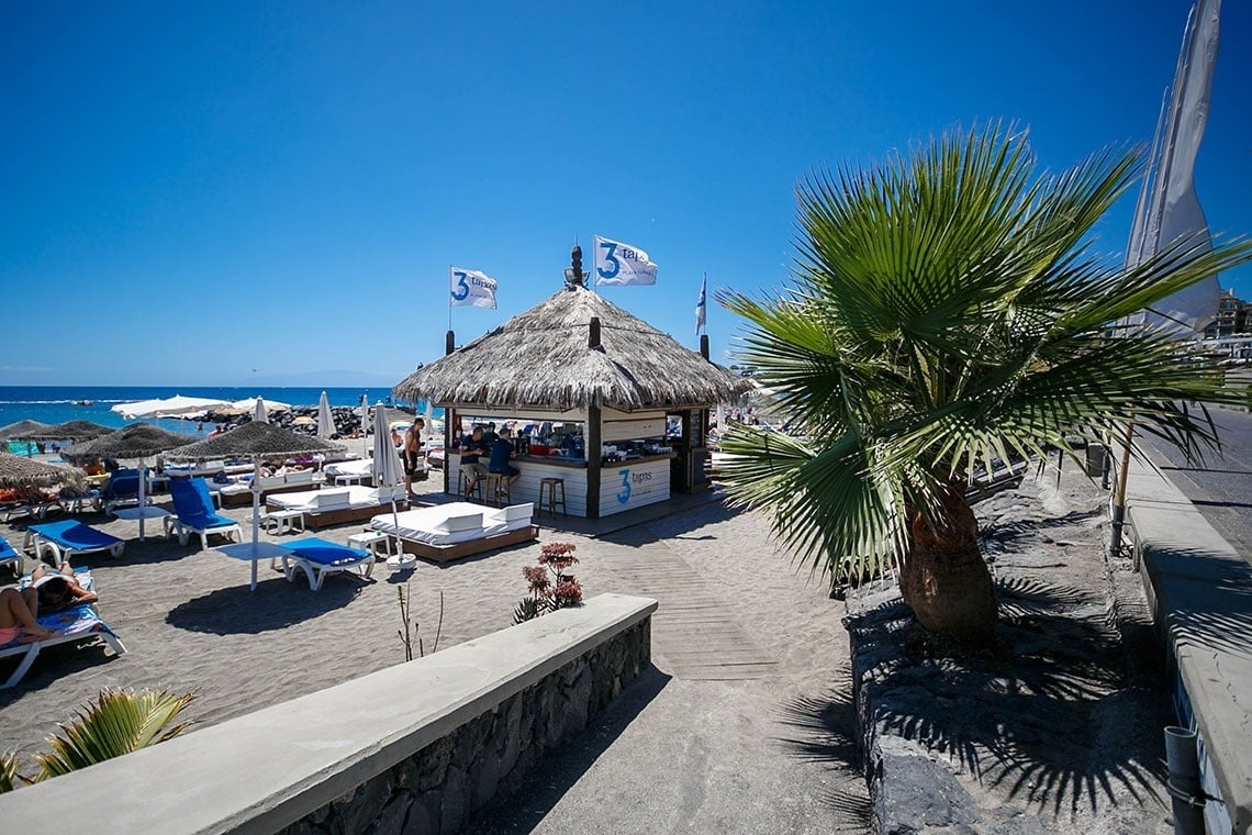 a beach with a thatched hut and flags with the number 3 on them