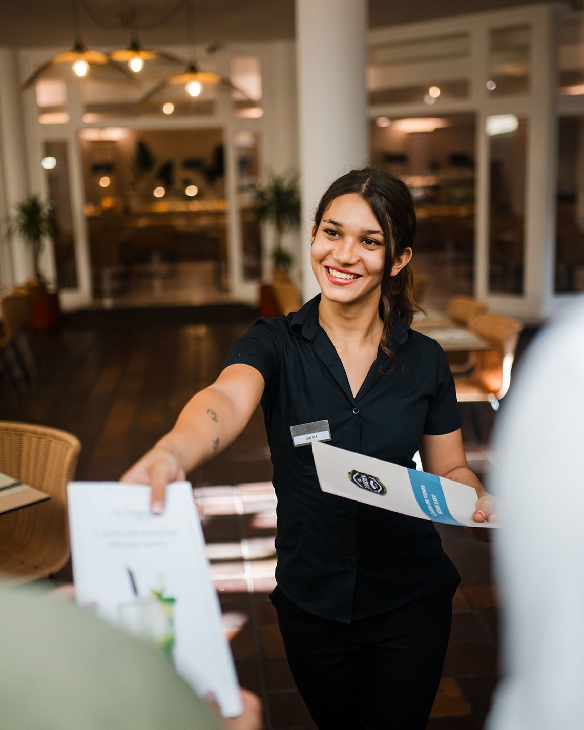 a woman in a black shirt is holding a menu for a restaurant