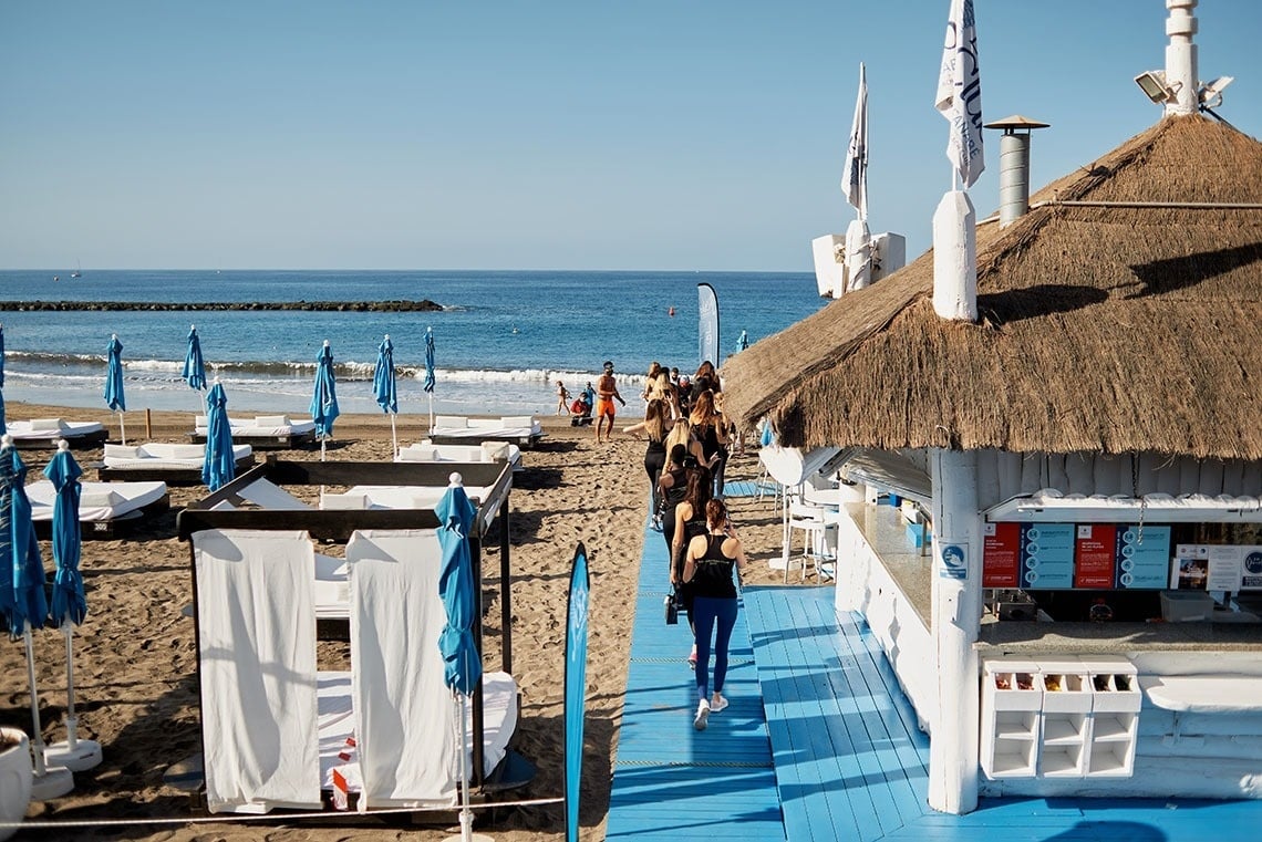 a woman walks towards a thatched hut on the beach