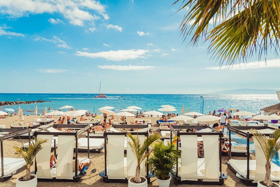 a beach with a lot of white chairs and umbrellas