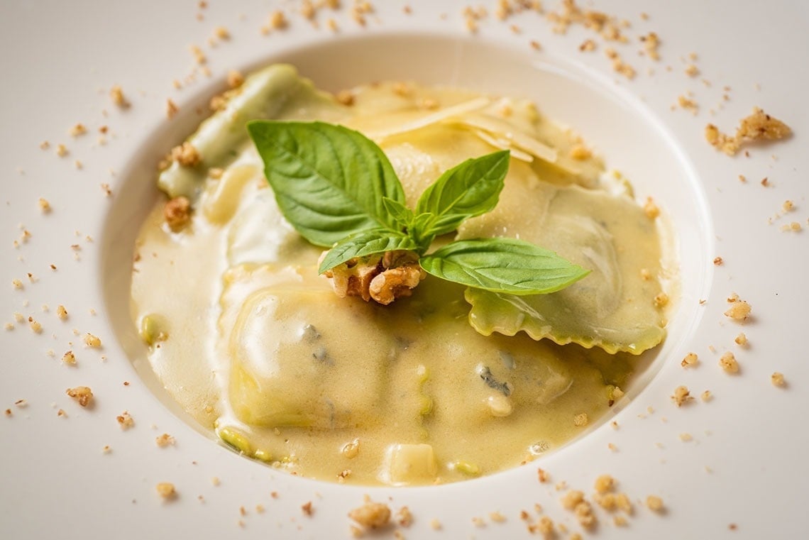a plate of ravioli with a basil leaf on top