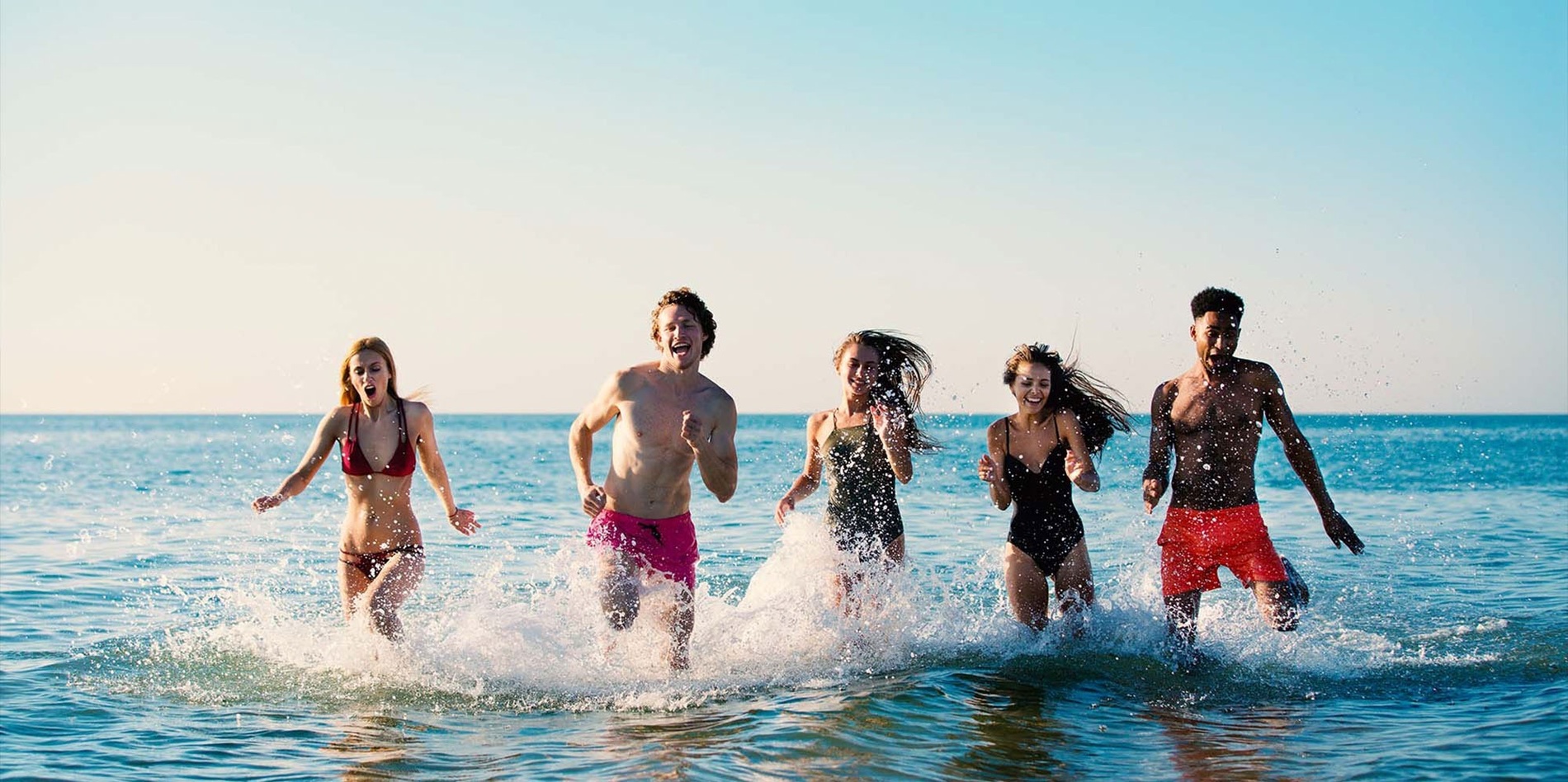 un grupo de jóvenes corre hacia el océano