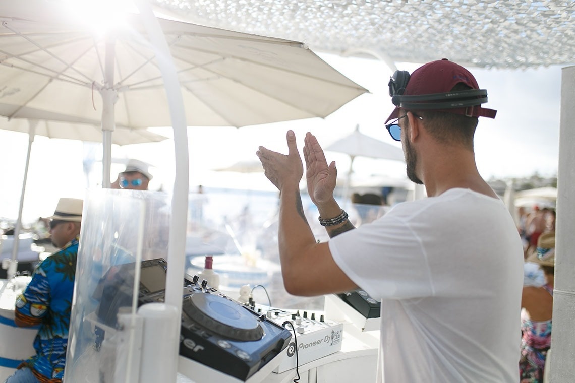 a man wearing headphones stands in front of a pioneer dj machine