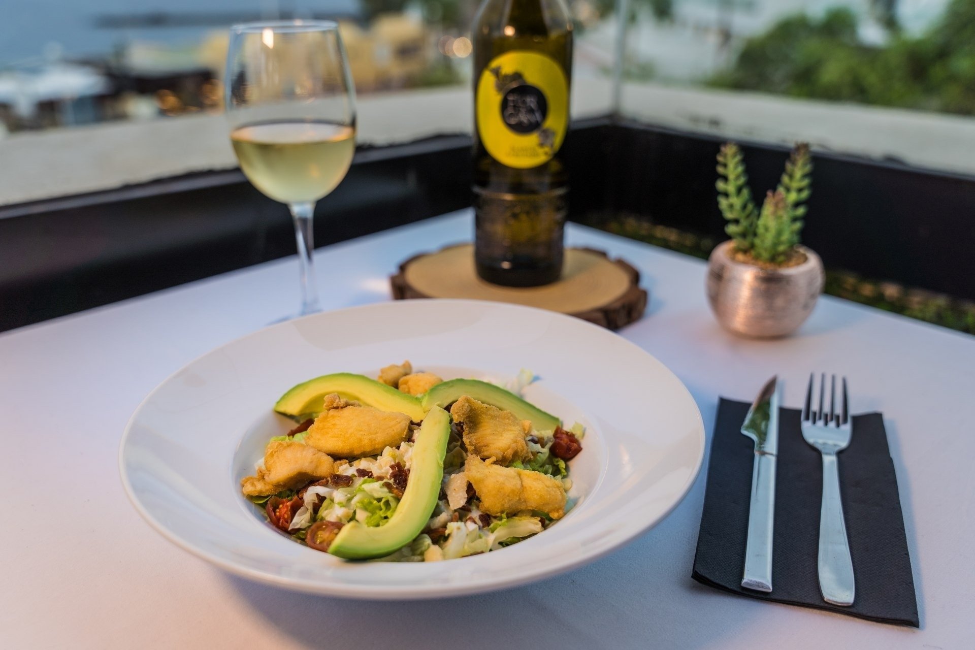 a bottle of alba sits on a table next to a plate of food
