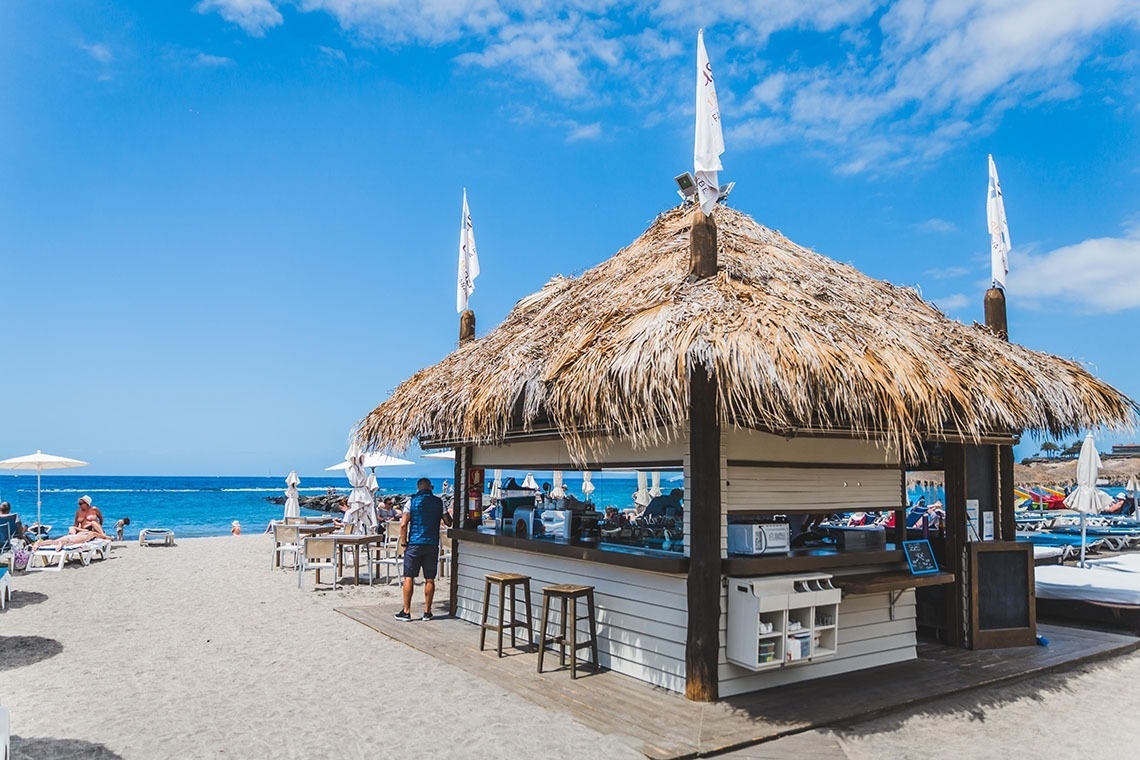 a thatched hut on a beach with a sign that says ' coca cola ' on it
