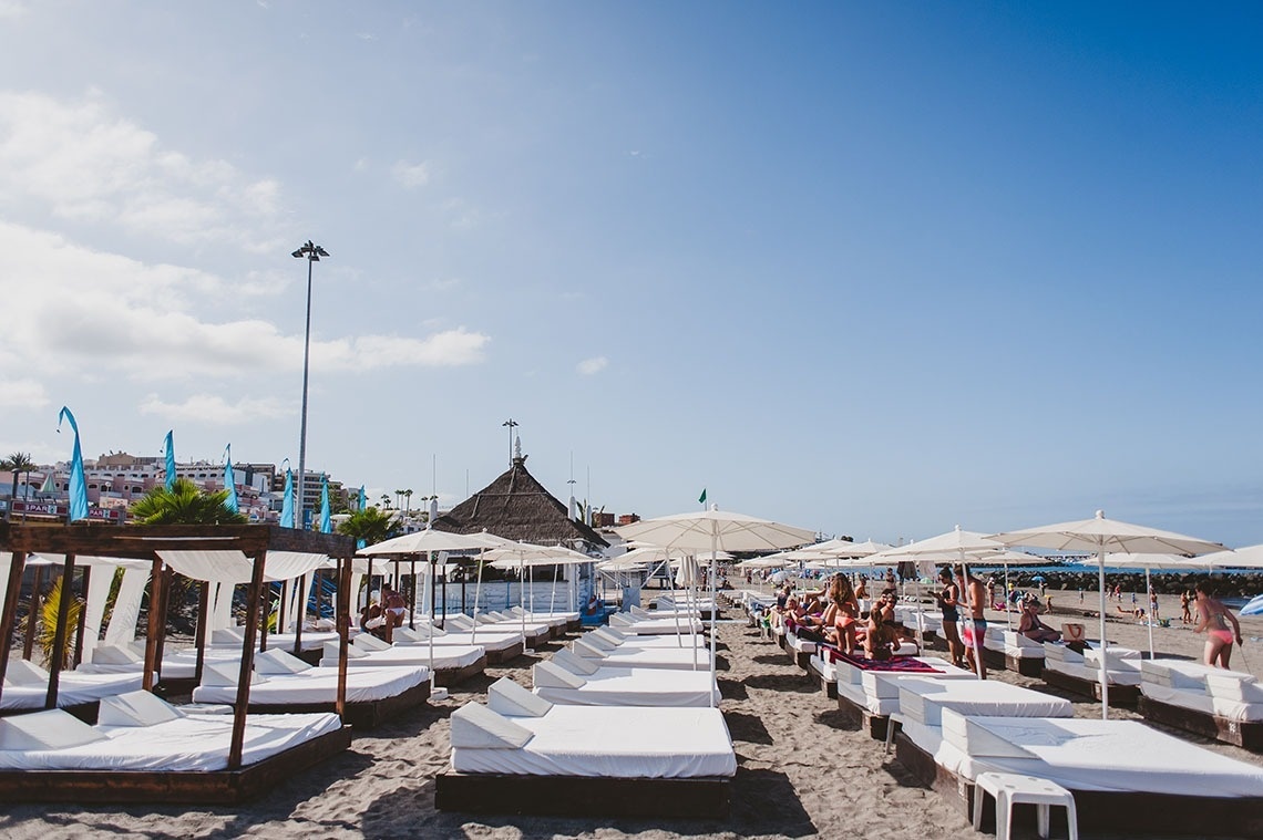 a beach with lots of white beds and umbrellas