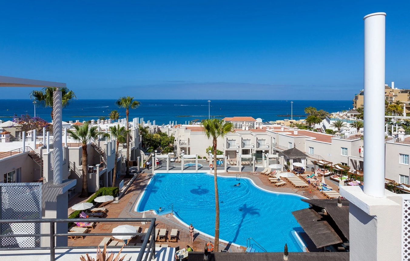 a large swimming pool is surrounded by palm trees and buildings