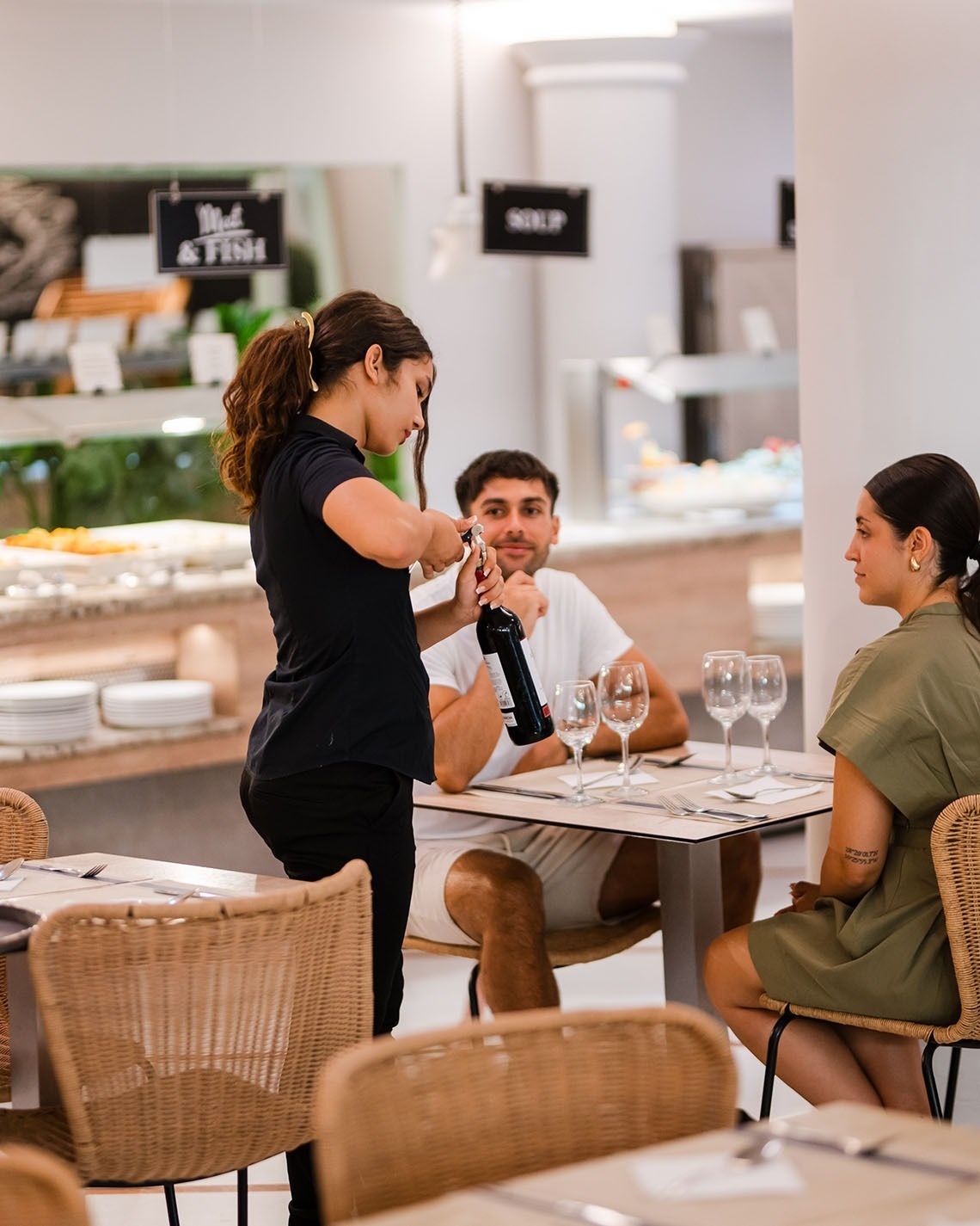 a waitress is serving a man a bottle of wine at a restaurant