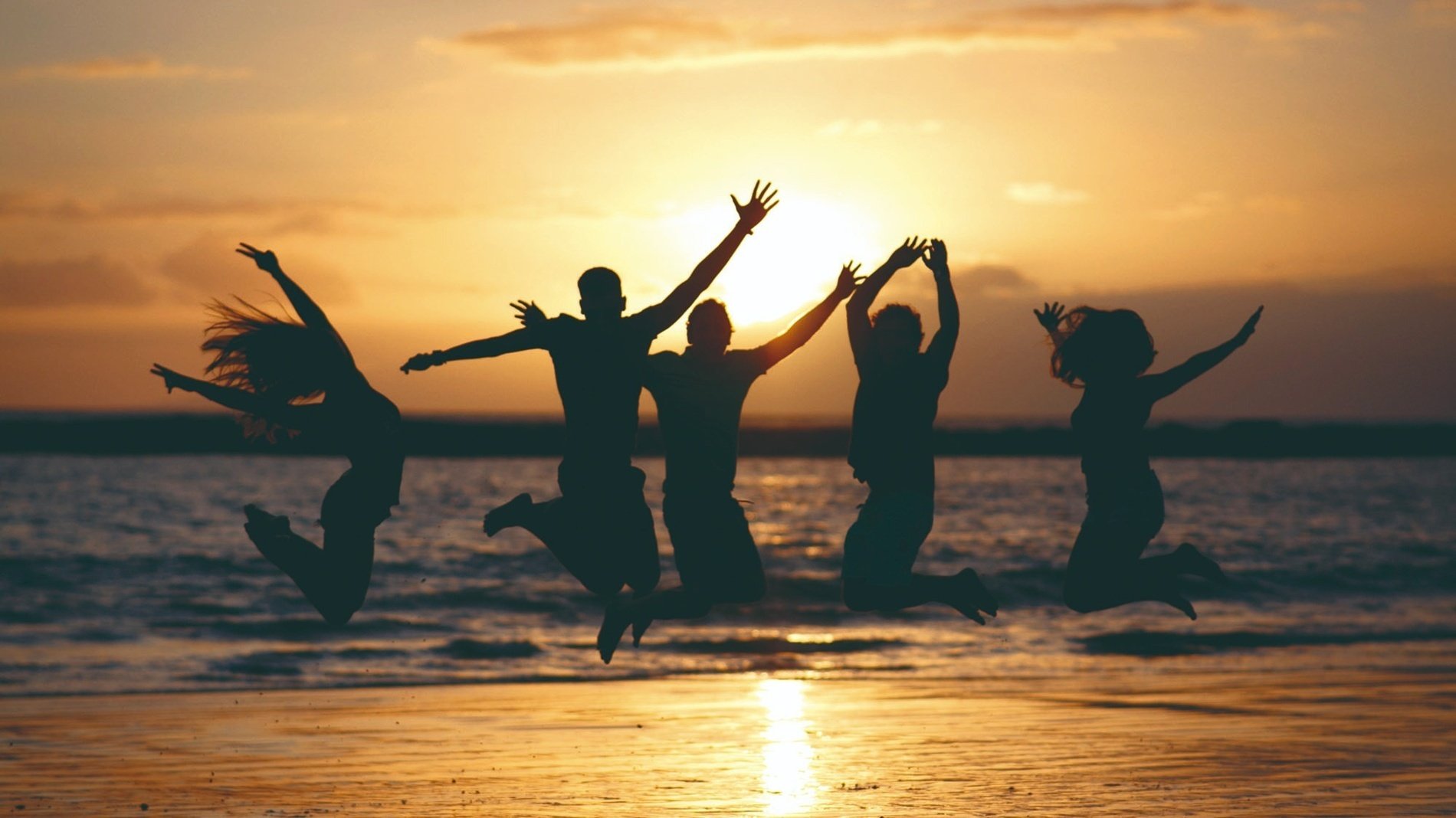 eine Gruppe von Menschen springt bei Sonnenuntergang in die Luft