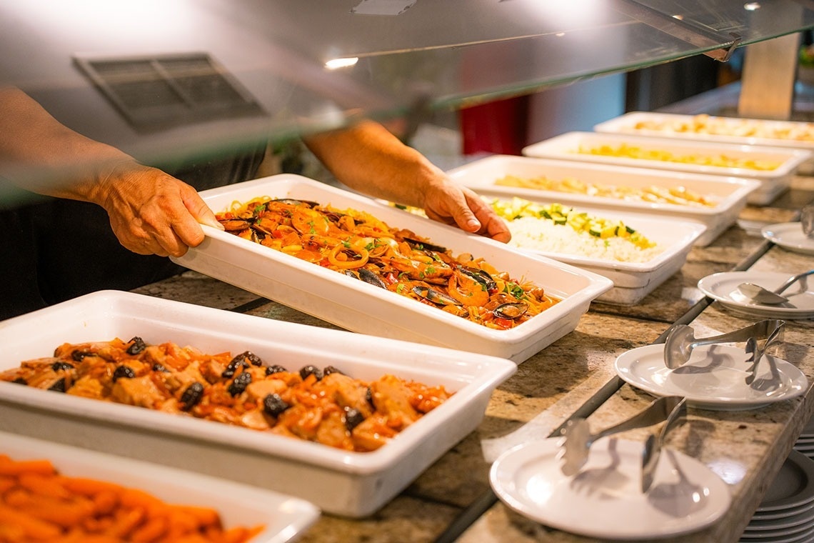a person taking a tray of food from a buffet line