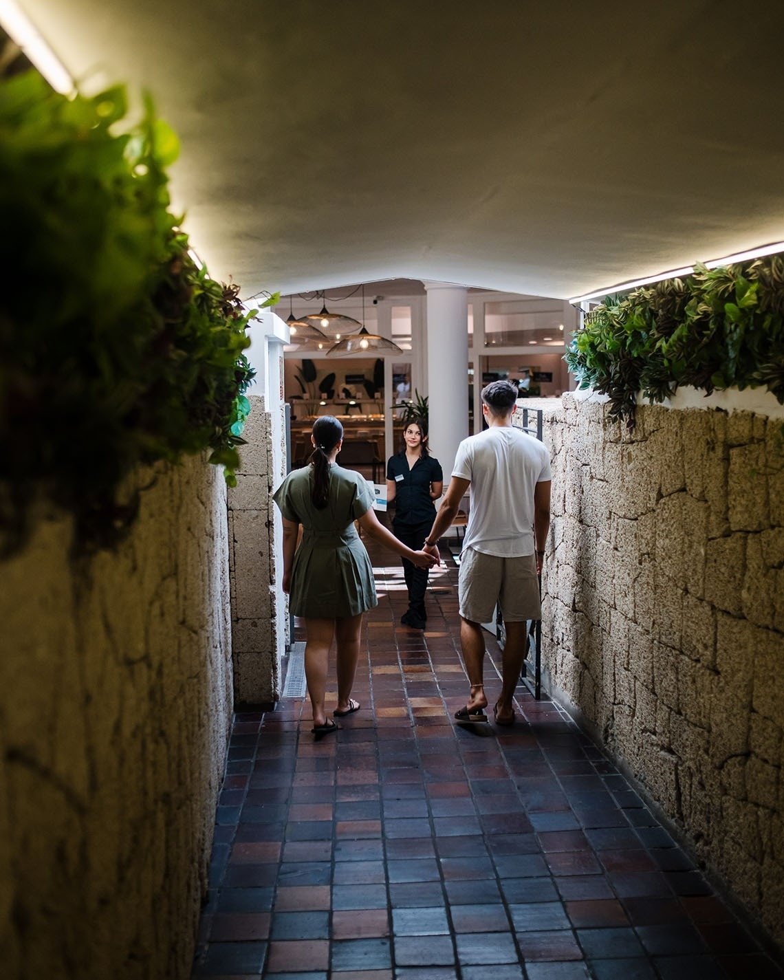 a man and woman walking down a hallway holding hands
