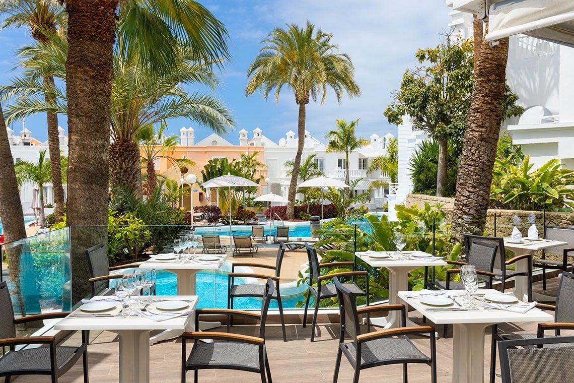 a restaurant with tables and chairs in front of a pool