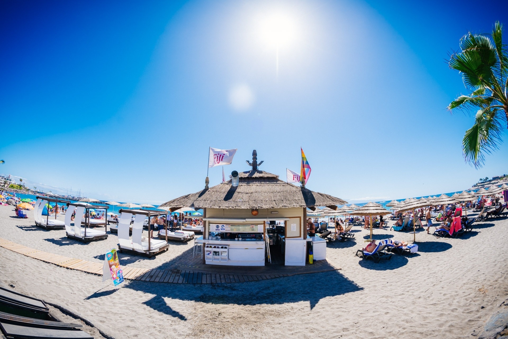 a thatched hut on a beach with a sign that says ' tm ' on it