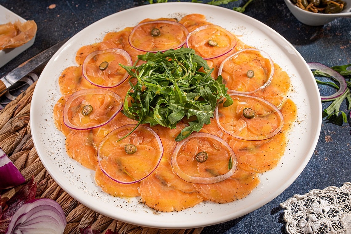 a white plate topped with sliced salmon and onions