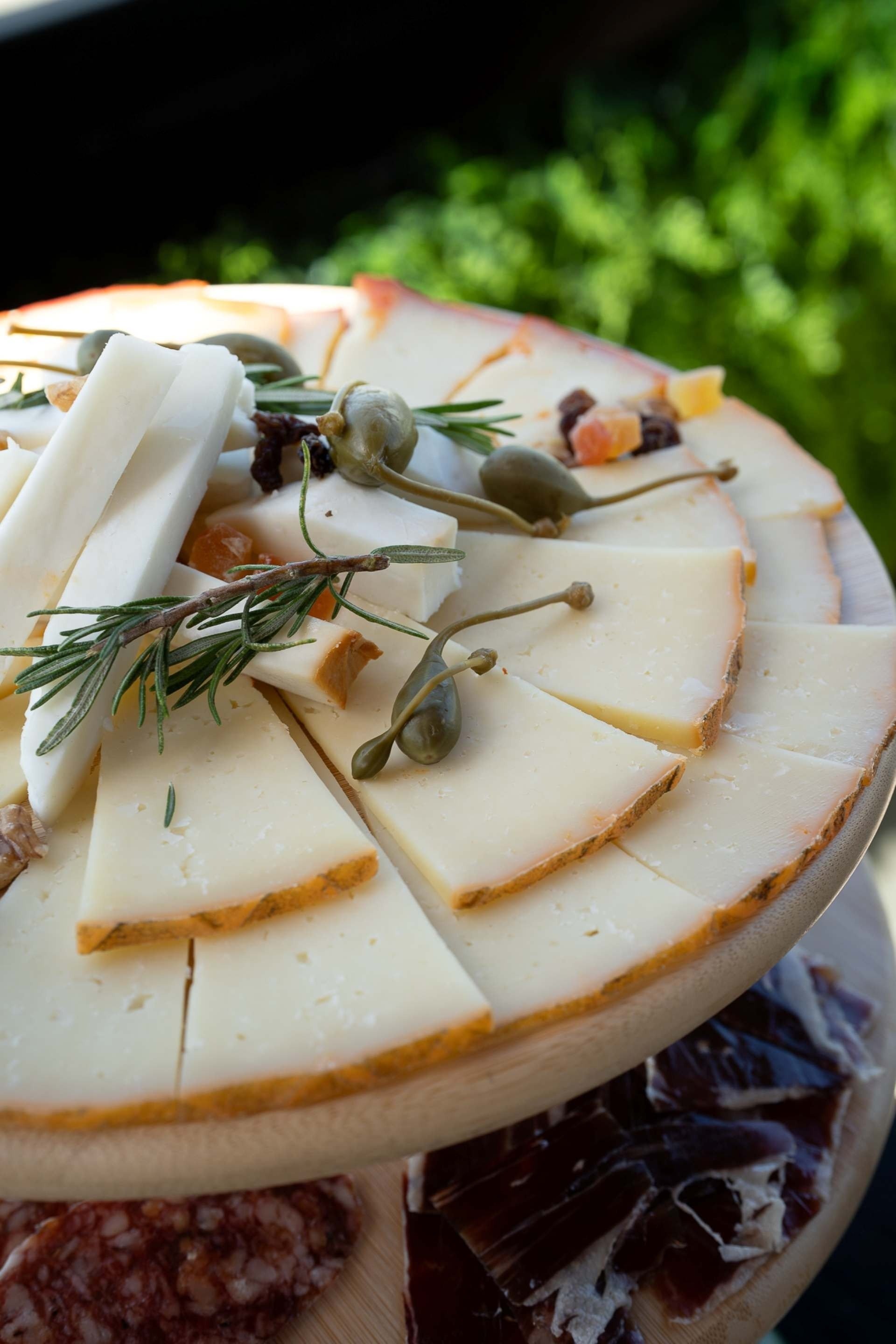 a wooden cutting board with slices of cheese and olives on it