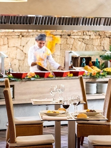 a restaurant with a chef preparing food in the background