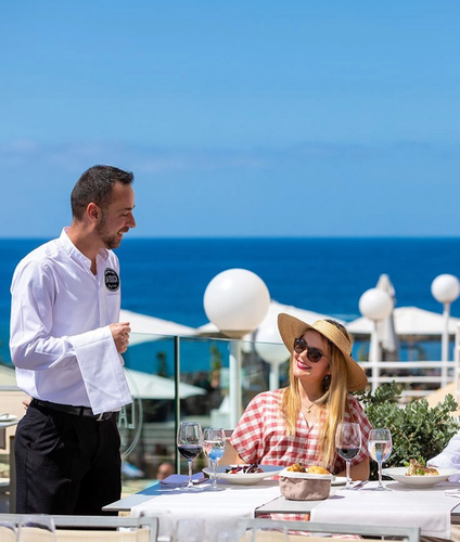 a waiter is serving a woman at a table with a sign that says al