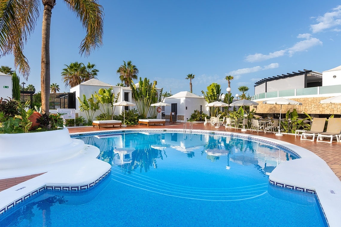 a large swimming pool surrounded by white chairs and umbrellas