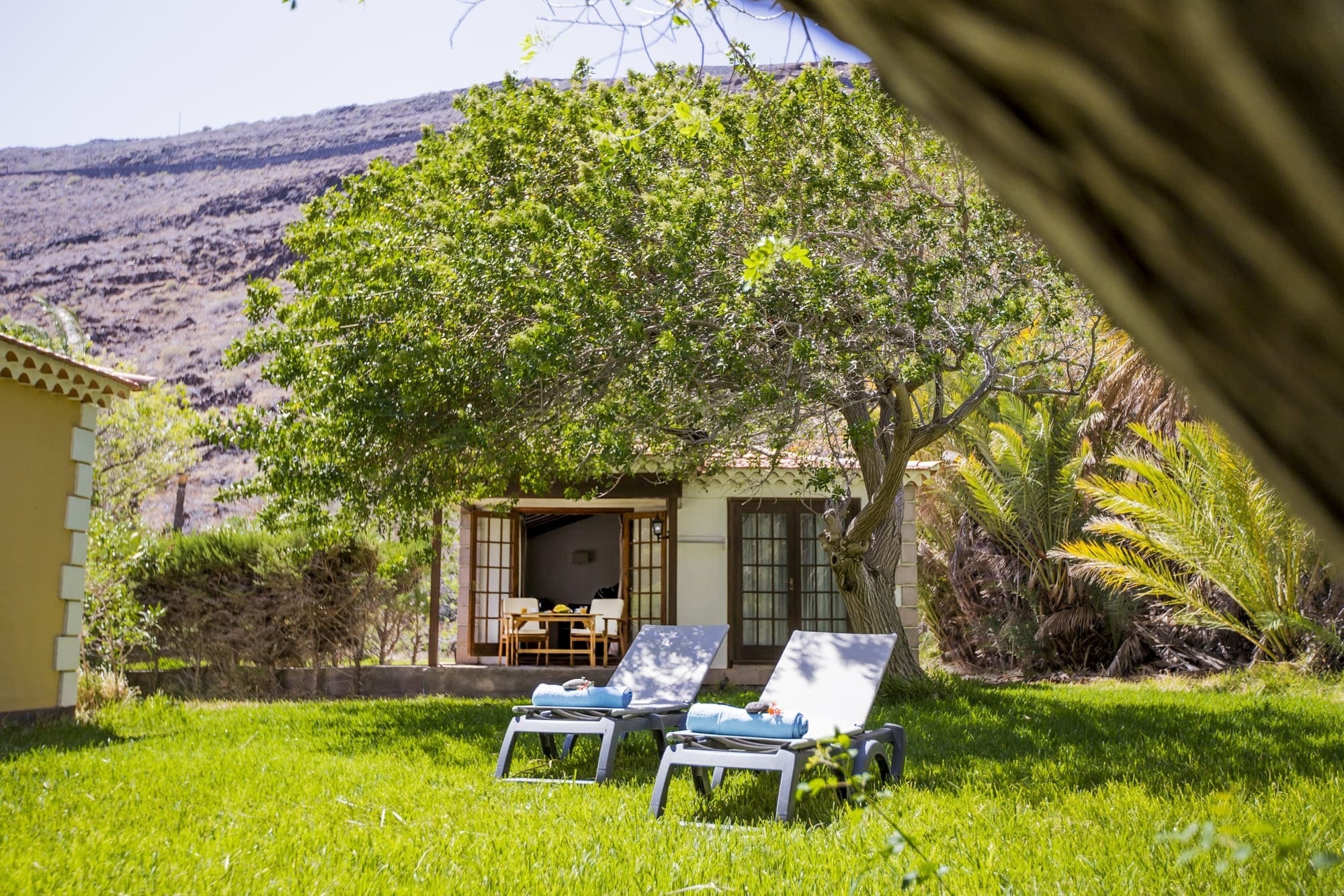 lawn chairs in front of a house with a mountain in the background