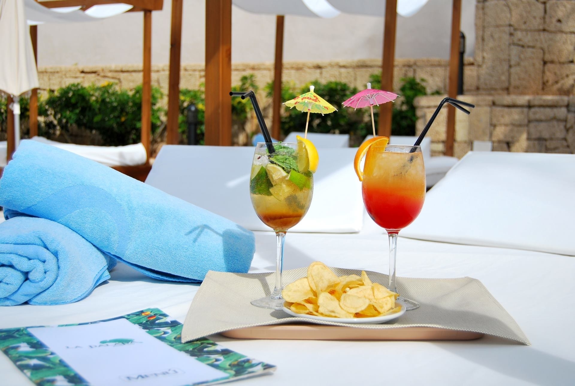 a tray of chips sits next to two drinks with umbrellas on them