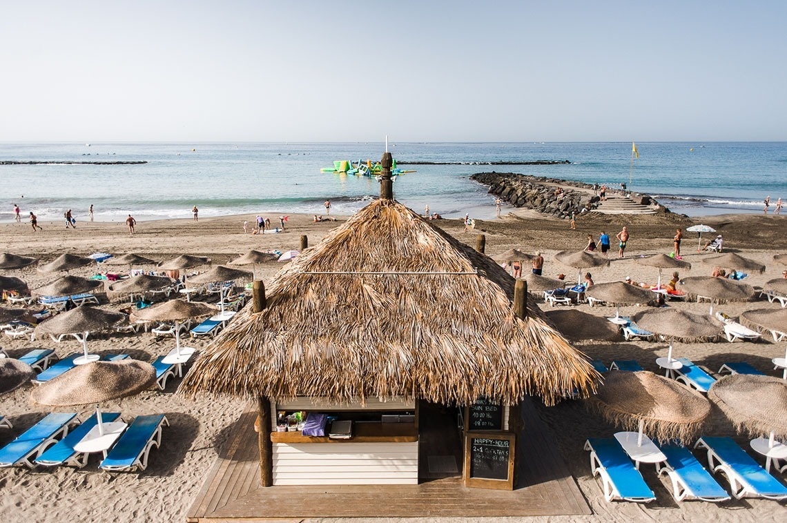 a thatched hut on a beach with a menu on it