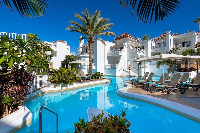 a woman in a bathing suit sits on the edge of a swimming pool