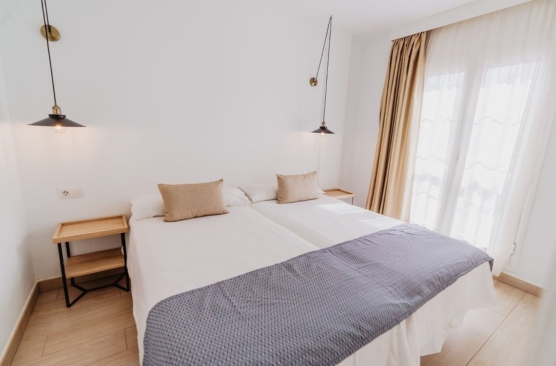 una habitación con dos camas y dos mesitas de noche