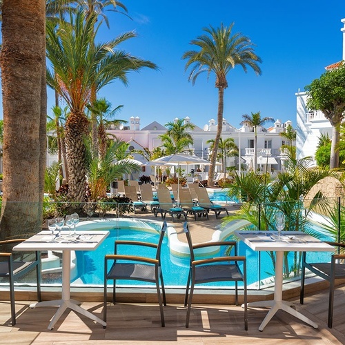 tables and chairs in front of a swimming pool