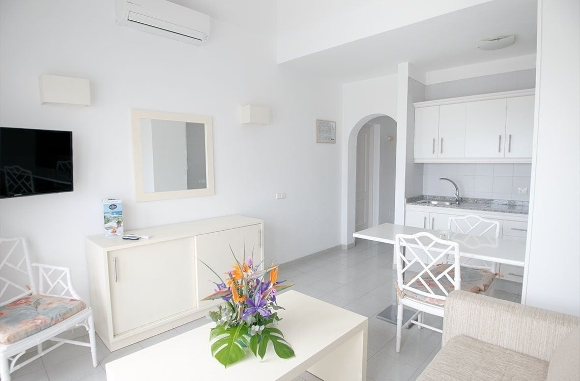 una habitación blanca con una mesa y sillas y un televisor