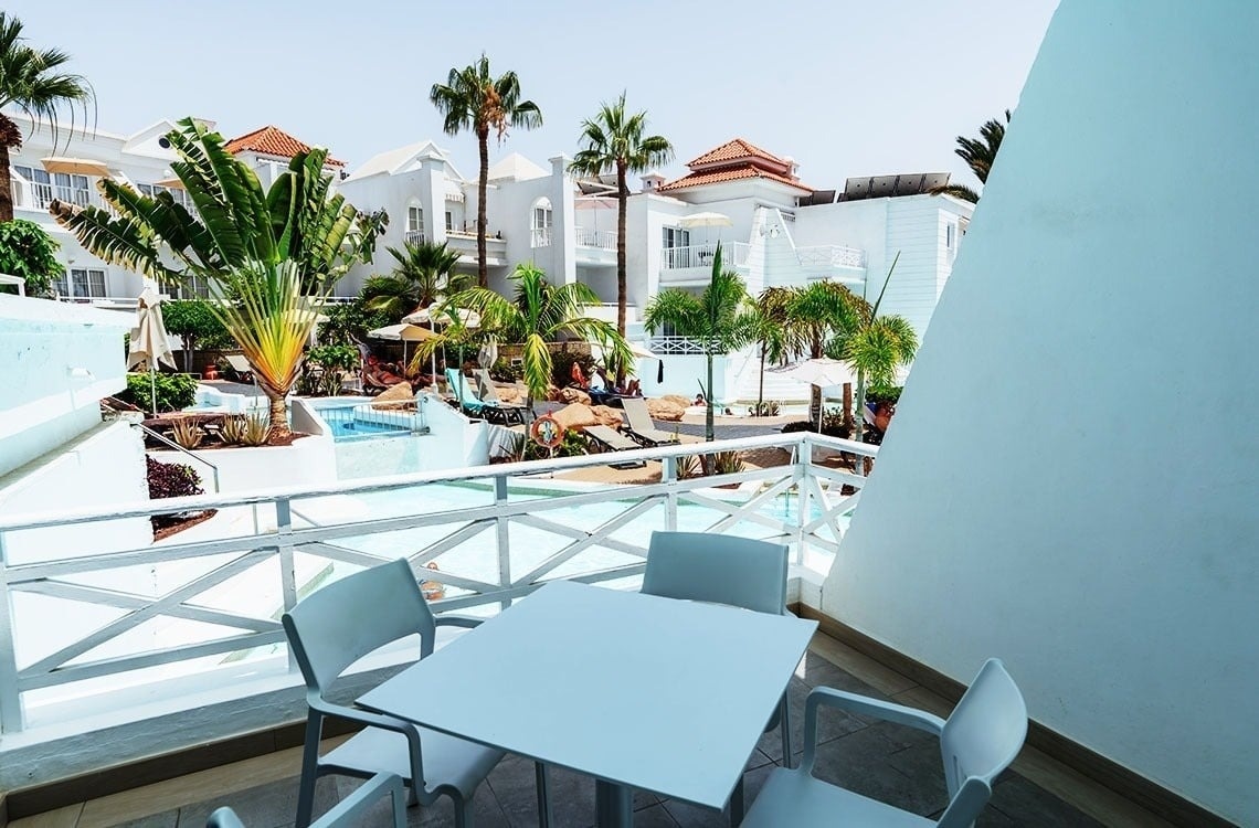 una mesa y sillas en un balcón con vistas a una piscina