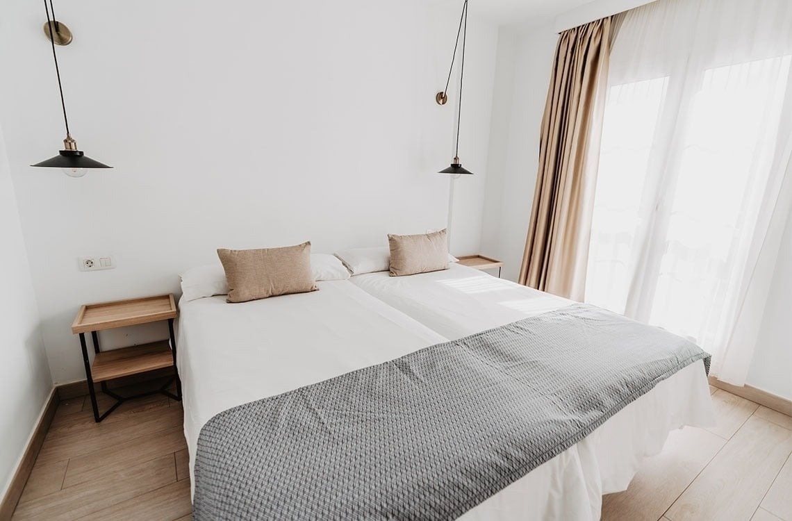 una habitación con dos camas y dos mesitas de noche