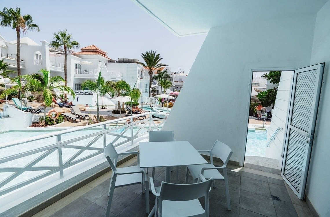 una mesa y sillas en un balcón con vistas a una piscina