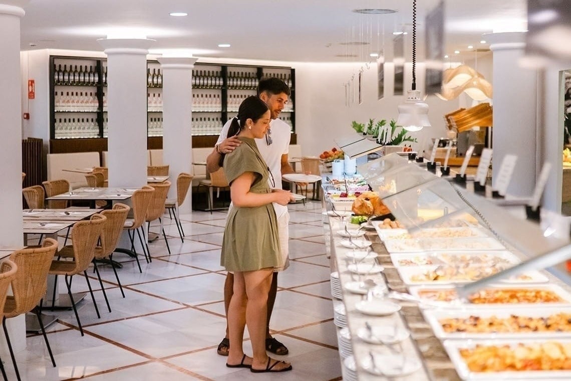Pareja disfrutando un buffet variado en el restaurante moderno del hotel.