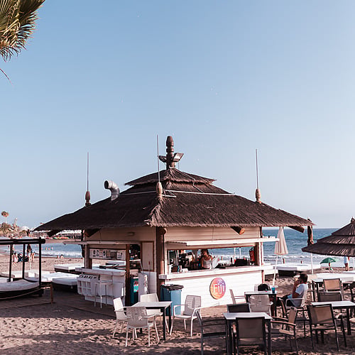 Beach Club with a thatched roof and outdoor tables.