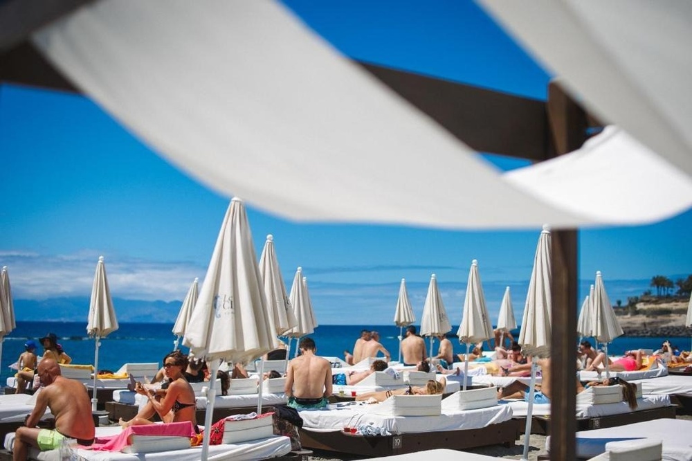 una terraza con mesas y sillas y sombrillas en un día soleado