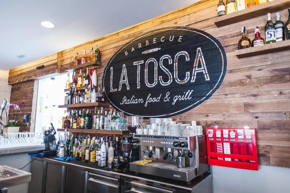 una terraza con mesas y sillas y sombrillas en un día soleado