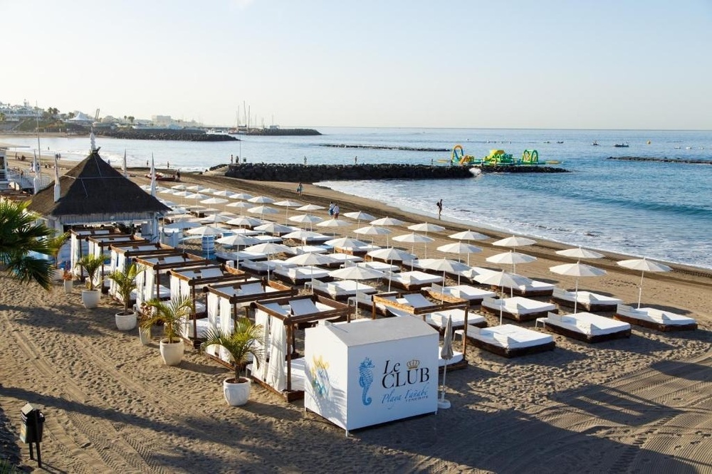 una mujer en traje de baño y sombrero se sienta junto a una piscina