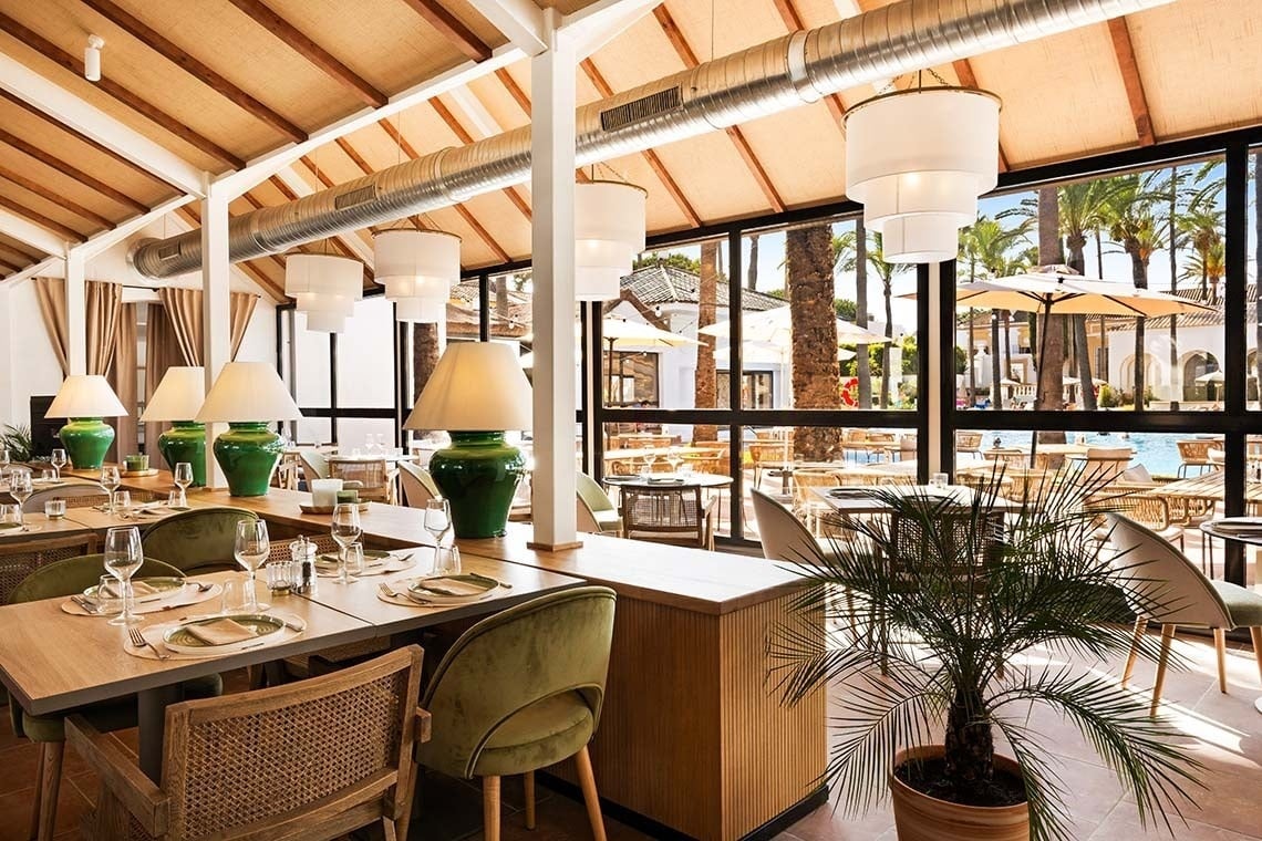 un restaurante con mesas y sillas verdes y lámparas verdes