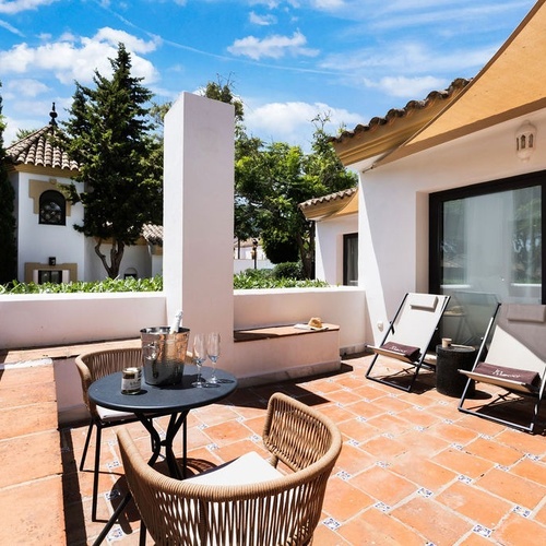 a balcony with two chairs and a table with a bottle of champagne on it
