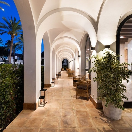 a long hallway with arches and a plant in the middle