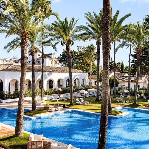 a large swimming pool surrounded by palm trees and chairs