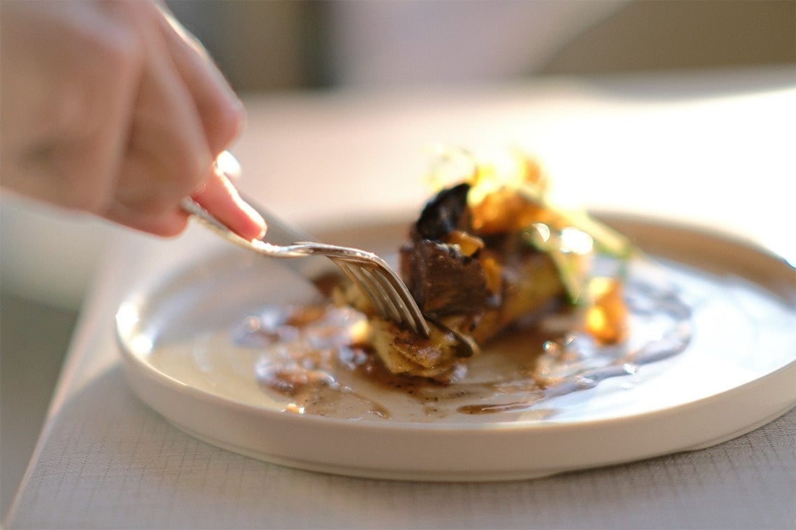 una persona sostiene un tenedor sobre un plato de comida