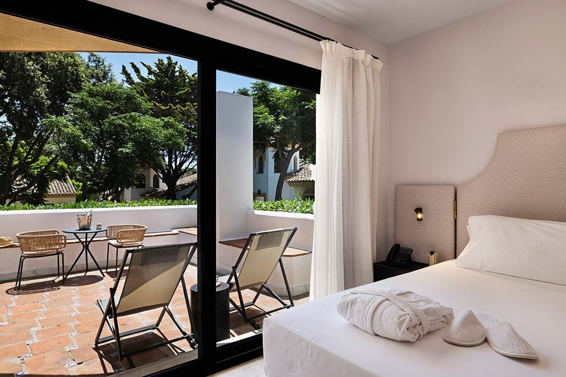 una silla blanca está sentada en una habitación junto a una ventana