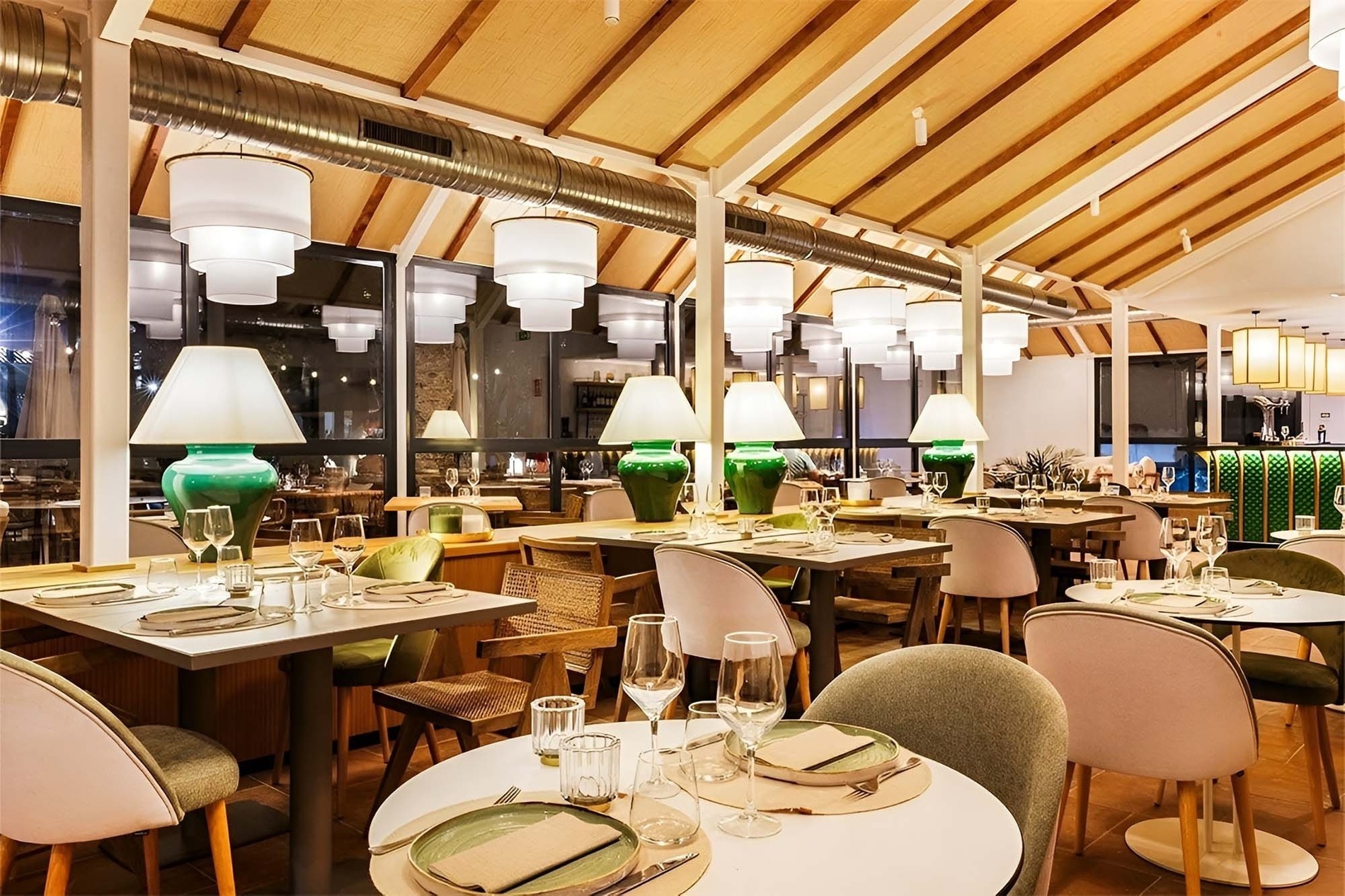 Elegante restaurante de hotel con mesas preparadas, sillas modernas y distintiva iluminación colgante.