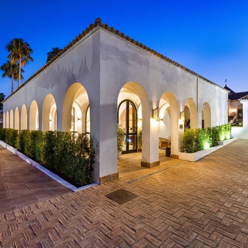 a white building with arches and a brick walkway