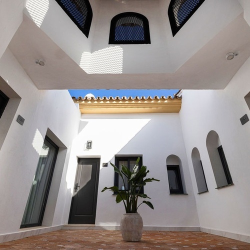a white building with black doors and a plant in the middle